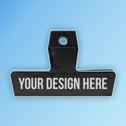 A photo of a wide black plastic clip with YOUR DESIGN HERE printed on it in white.