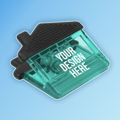 A photo of a clip shaped like a house, made of transparent green plastic, printed with YOUR DESIGN HERE in white, with a black opaque roof.
