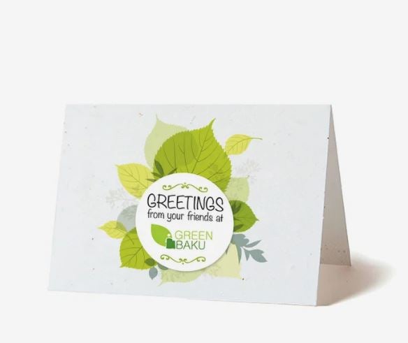 A photo of a card made from seed paper folded at the top, with a design of green leaves and Greetings from your friends at Green Baku printed on the front.
