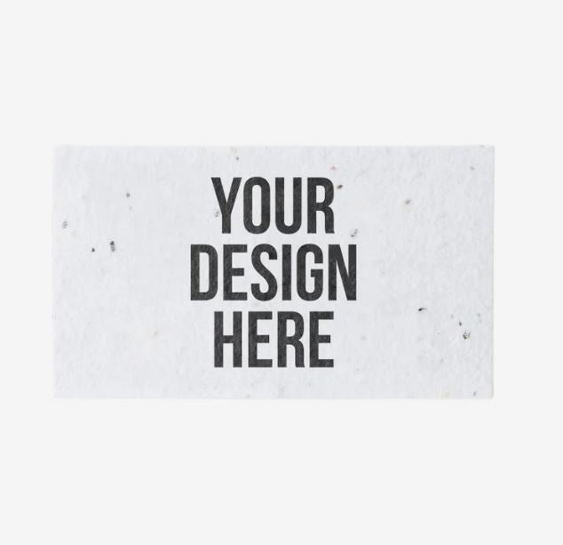 A photo showing a rectangular white business card made of seeded paper, with YOUR DESIGN HERE printed on the front in black.