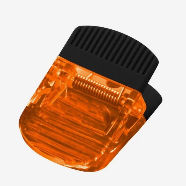 A photo of a transparent orange plastic clip.