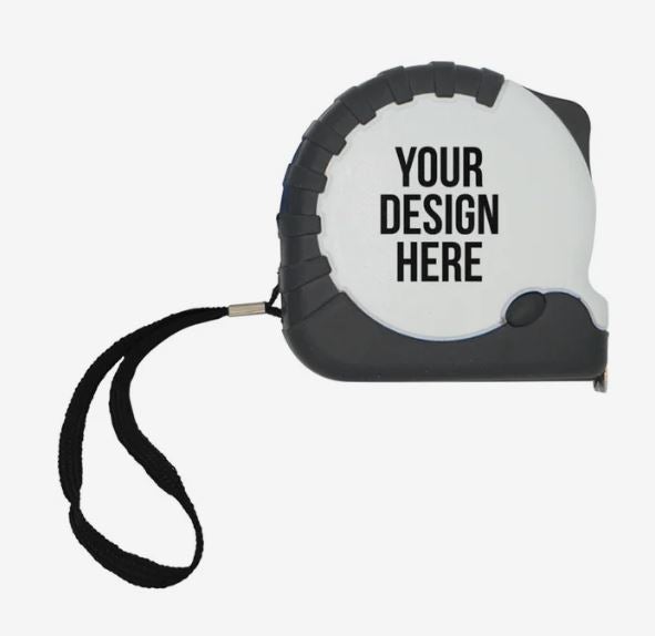 A photo of a white metal tape measure with YOUR DESIGN HERE printed on it in black and a black wrist strap.