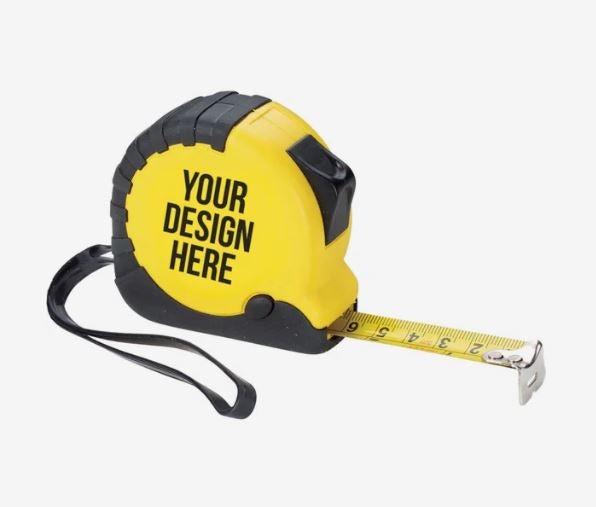 A photo of a yellow and black metal tape measure with YOUR DESIGN HERE printed on it in black, and a black wrist strap.
