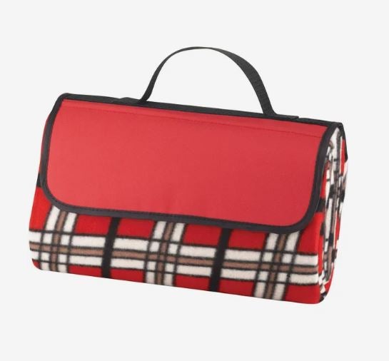 A photo of a plaid tartan picnic blanket, folded with a handle on the top.