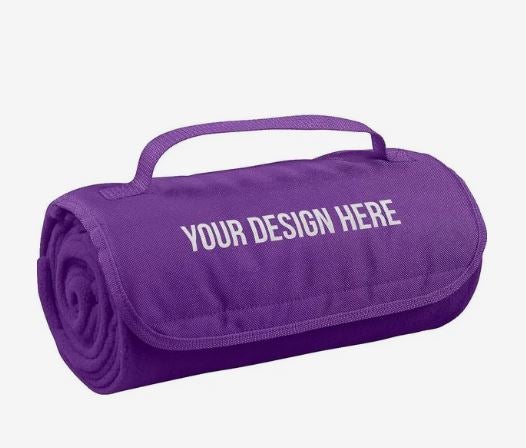 A photo of a purple rolled up fleece blanket with a strap and YOUR DESIGN HERE on the front.