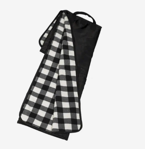 A photo of a black and white checked blanket, partly unfolded from a black case.