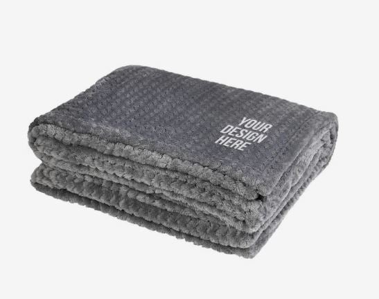 A photo of a soft grey folded blanket, decorated with YOUR DESIGN HERE on the top.
