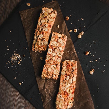 A photo of three granola bars on a wooden slab.