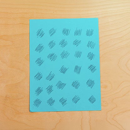 A photo showing a piece of blue construction paper with 30 pencil scribbles in a grid.