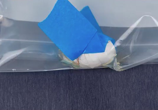 A zoomed in photo showing a cracked egg in a clear plastic bag.