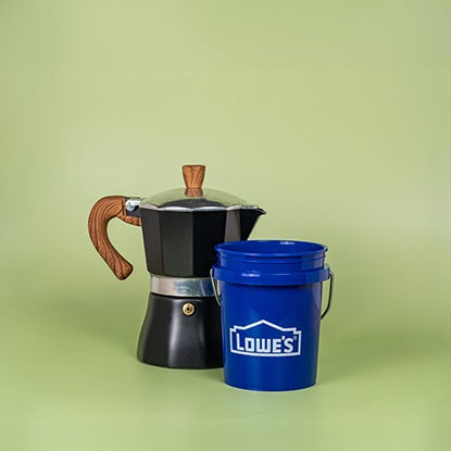 A photo of a blue mini Lowe’s bucket next to a stovetop coffee maker.