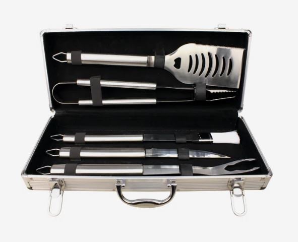 Stainless steel barbecue tool set with spatula, tongs, fork, basting brush, and other grilling accessories arranged in an open silver carrying case with black lining.
