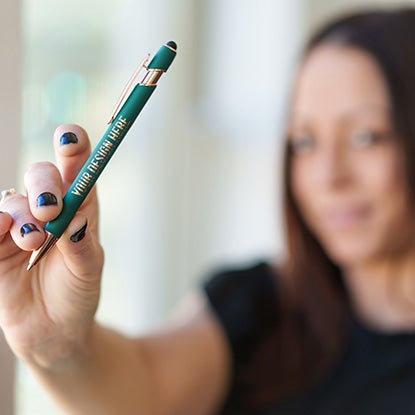 A photo of a woman holding a green pen towards the camera.
