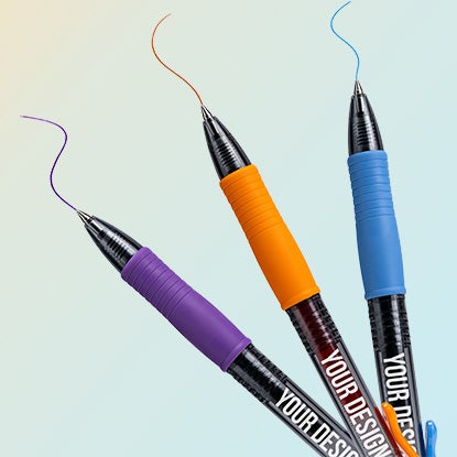 A photo of three pens with plastic black barrels. Each one has a different colored grip, in purple, orange and blue, and is drawing a squiggly line in a matching color.
