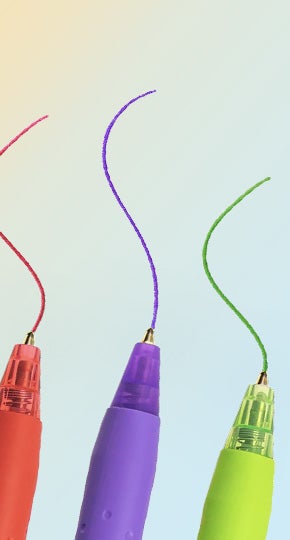 A close-up of three pens, in red, purple and green, each drawing a matching squiggly line.