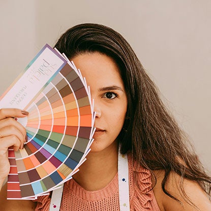 A photo showing a person holding a fan of color cards over half of their face.