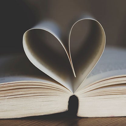 A photo showing an open book with the center pages folded into a heart shape.