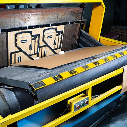 A photo showing a die cutter cutting out a piece of cardboard.